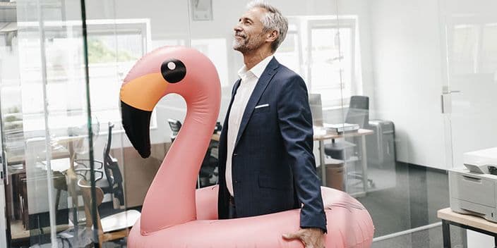 Mann im Anzug trägt Flamingo-Schwimmring